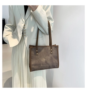 Detail of vintage tote bag featuring brown cloud-texture material and gold rivet accents