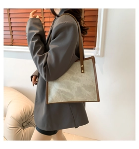 Detail of grey vintage tote bag with brown leather straps and gold metal rivets