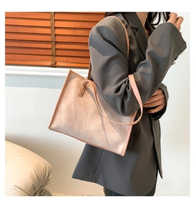 Detail view of pink suede tote bag with slim contrast straps on a model in grey suit