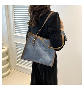 Detail of marble pattern tote bag with brown leather handles and metal rivets