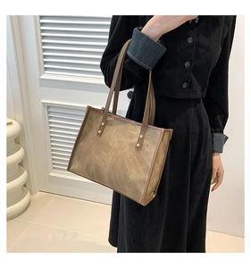 Detail of vintage brown tote bag showing wrinkled leather texture and metal rivets