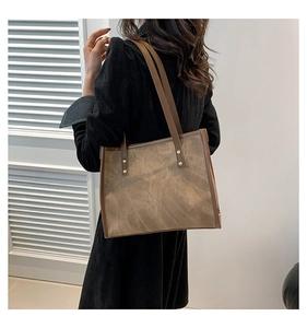 Close-up of brown vintage leather tote bag with marbled texture and golden rivets details