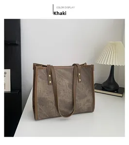 Detail of khaki tote bag with marble texture and gold rivets on a white table