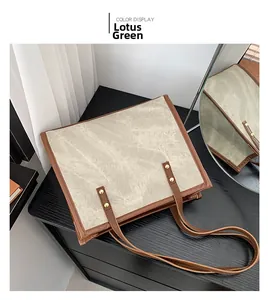 Detail view of lotus root green tote bag with brown leather trim and golden rivets
