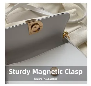 Détail d'un fermoir magnétique doré solide sur un sac à main en cuir blanc raffiné