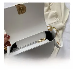 Gros plan du sac besace blanc avec poche zippée et détails de chaîne dorée