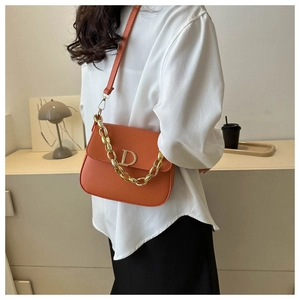Détail du sac selle orange avec fermoir métallique doré en D et poignée chaîne