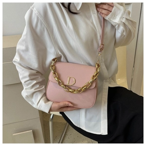 Détail du sac selle en cuir rose avec anse chaîne dorée et boucle métallique en D
