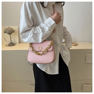Détail du sac selle en cuir rose avec boucle 'D' dorée et bandoulière chaîne