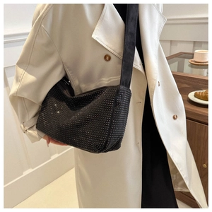 Sac hobo noir à strass tendance avec large bandoulière porté sur un trench-coat blanc