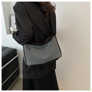 Close-up of a sparkling black rhinestone shoulder bag on a model in a modern interior