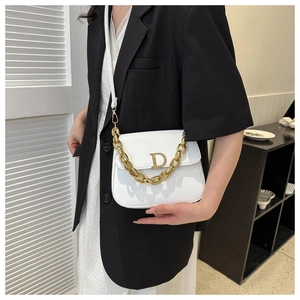 Détail d'un sac selle blanc avec boucle logo D dorée et poignée en chaîne épaisse