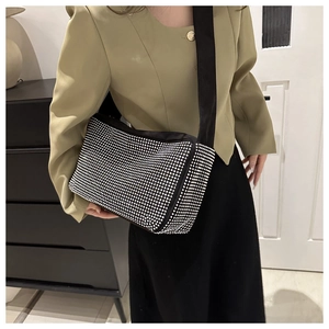 Détail du sac à strass noir avec large bandoulière porté sur un costume vert chic