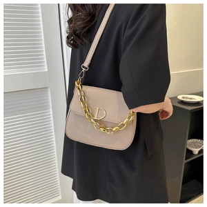 Détail du sac selle en cuir verni beige avec boucle D dorée et bandoulière chaîne