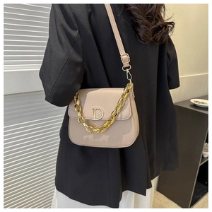 Détail du sac selle beige avec grosse chaîne dorée et décoration métallique en lettre D