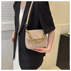 Détail du mini sac beige avec boucle logo D dorée et décoration de chaîne épaisse