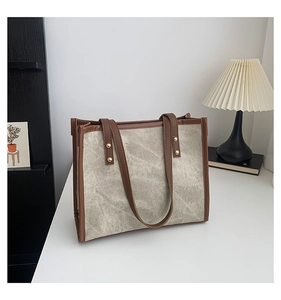 Retro grey canvas tote bag with brown leather trim in a minimalist home setting