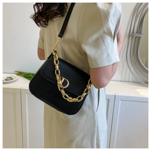 Détail du sac à rabat en cuir noir avec chaîne dorée et logo D métallique sur le rabat