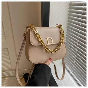 Détail du sac selle beige avec logo D doré et bandoulière en chaîne métallique