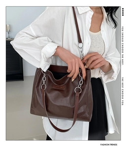 Close-up of brown crocodile pattern tote bag featuring stylish silver chain link strap