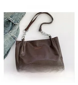 Detail of dark brown faux crocodile tote bag with gold chain strap and fashion label