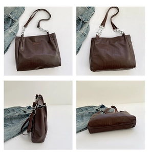 Detail of dark brown crocodile embossed tote bag with silver chain and leather straps