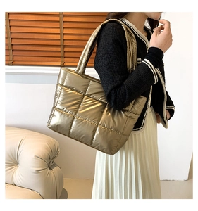 Close-up of golden quilted puffer tote bag with metallic finish worn on shoulder