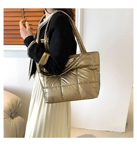 Side view of champagne gold quilted down tote bag worn on shoulder for style