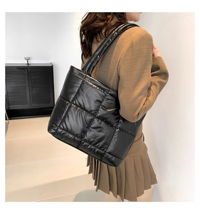 Detailed view of large black quilted puffer tote bag on model for size and style reference
