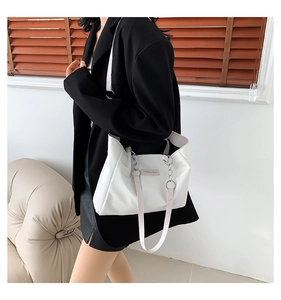 Detail of white leather tote bag with silver chain strap and fashion label on the front