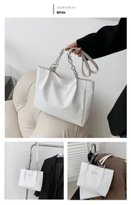 Detail of white crocodile pattern tote bag with metal chain strap and logo patch