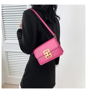 Detail of hot pink crossbody bag featuring a golden geometric lock and smooth leather