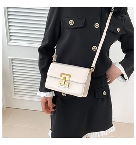 Close-up of cream square crossbody bag with gold geometric lock and sleek leather finish