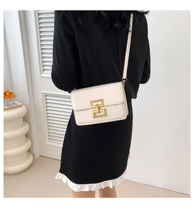 Side view of cream leather crossbody bag with a distinctive golden metal clasp