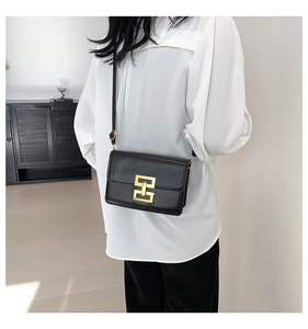 Detailed view of black leather shoulder bag featuring a gold rectangular metal lock