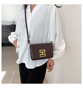 Detail of vintage brown leather crossbody bag with iconic interlocking gold metal lock