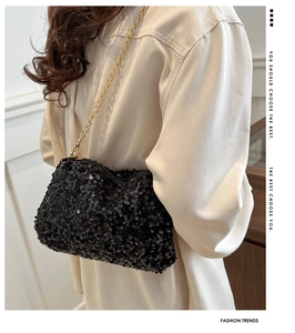 Detail view of a black sequin evening bag featuring a fine gold metal chain strap
