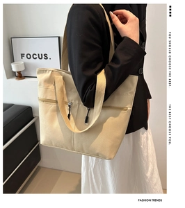 Gros plan détaillé d'un sac cabas en toile beige avec poche zippée et longues anses de transport