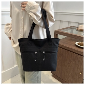 Détail du sac bandoulière en toile noire avec deux poches zippées verticales
