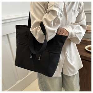 Détail du sac cabas en toile noire avec poche zippée et bandoulière large confortable