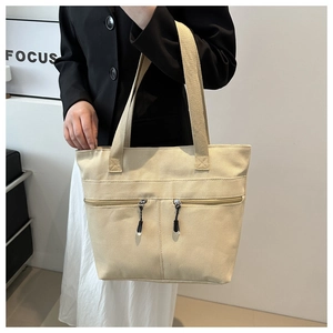 Détail du sac cabas en toile beige avec poches zippées et style rétro minimaliste