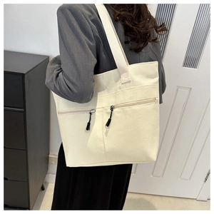 Grand sac cabas beige en toile avec fermetures éclair porté par un mannequin chic