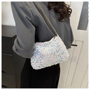 Detailed view of women's sparkling sequin crossbody bag with gold chain strap on model