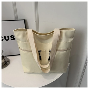 Détail du sac fourre-tout en toile blanc cassé avec doubles bretelles tissées et poche zippée