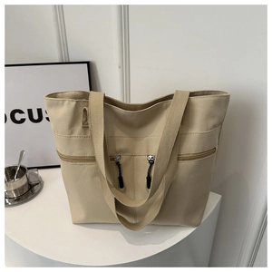 Détail du grand sac cabas en toile beige avec deux poches zippées et des bandoulières larges