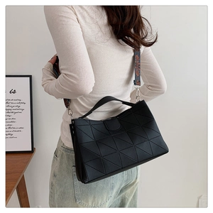 Detail of black geometric bucket bag featuring a colorful ethnic patterned wide strap