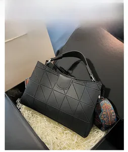 Close-up of black geometric embossed bucket bag with ethnic patterned wide strap in a gift box