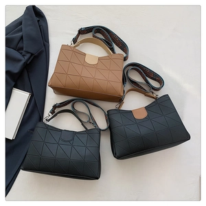 Close-up of geometric quilted bucket bags in black and brown with wide printed straps