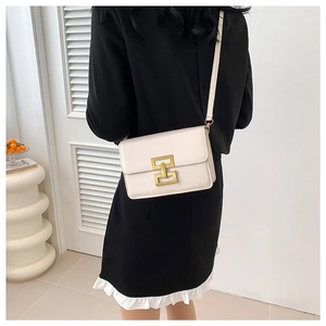 Elegant cream leather crossbody bag with golden geometric lock on a minimalist background