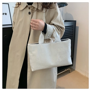 Minimalist white corduroy tote bag held by a model in a stylish trench coat